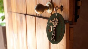 A wooden door with a brass doorknob and a keychain with a windmill design and the number 3. - Bella de Karoo (Oudtshoorn)