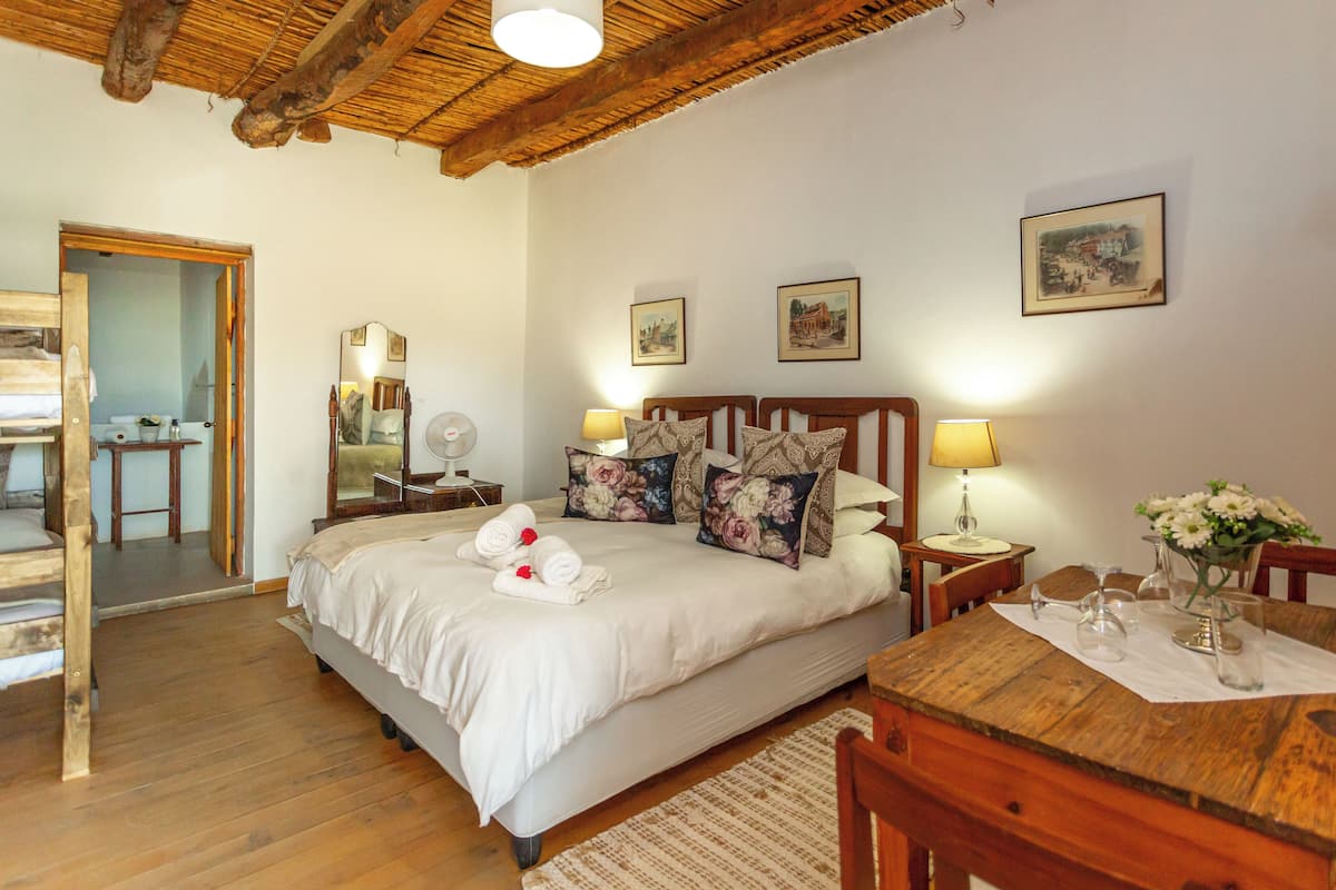 Un dormitorio con cama, mesitas de noche, un escritorio de madera y un espejo.