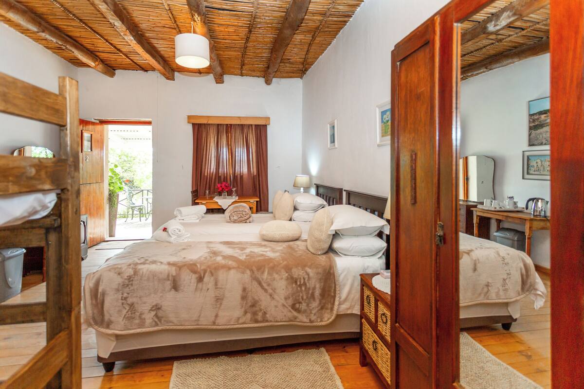 Un dormitorio con cama, muebles de madera, una ventana con cortinas y una puerta.