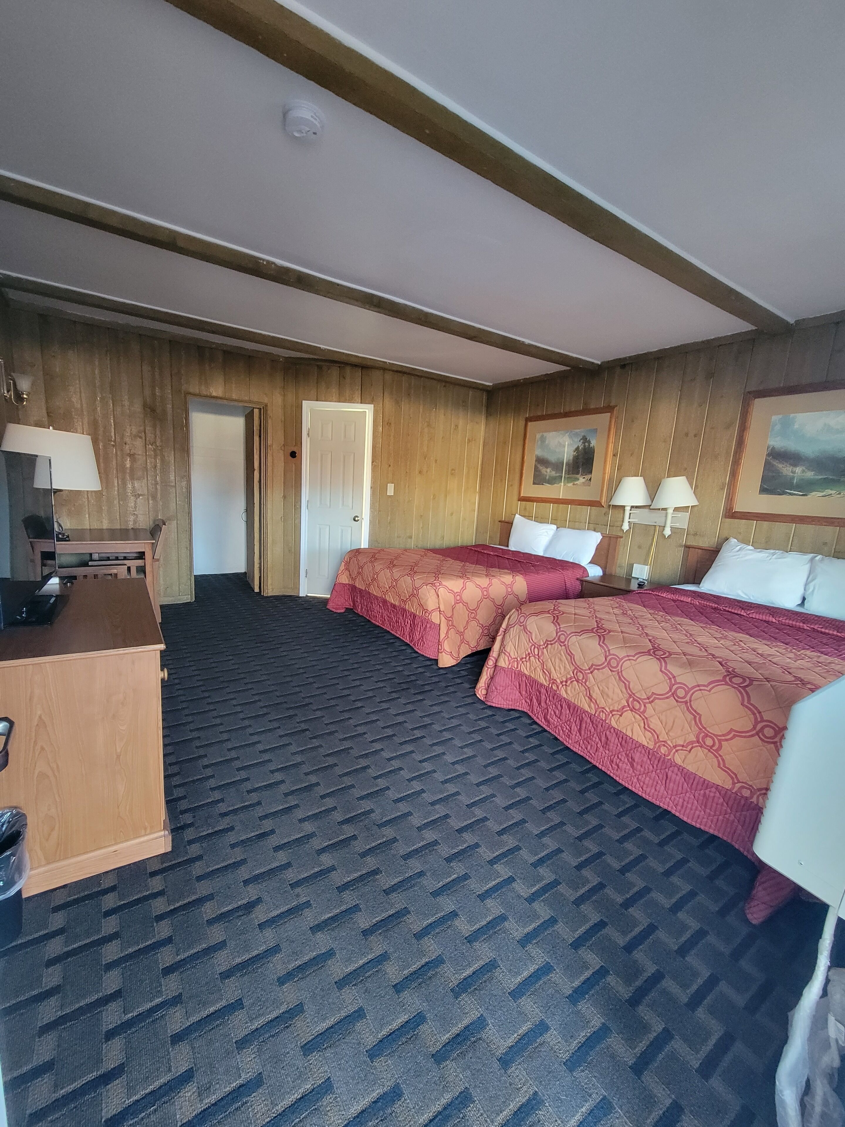 Une chambre d’hôtel avec deux lits, un bureau, une chaise, une armoire et une porte.