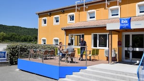 A hotel with outdoor seating and a sign reading "ibis budget."