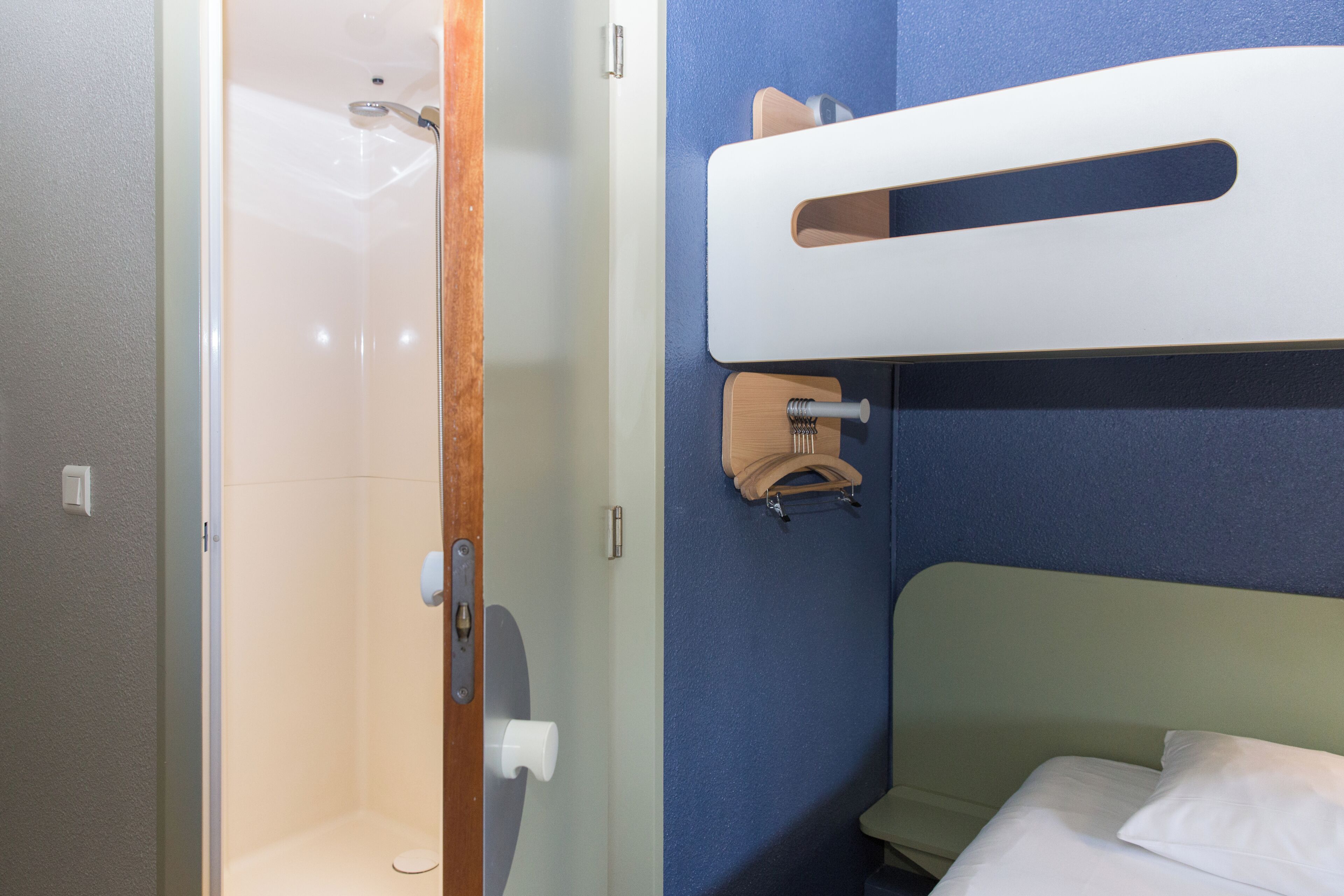 A bathroom with a shower, a toilet, and a bed with a headboard.