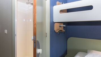 A bathroom with a shower, a toilet, and a bed with a headboard.