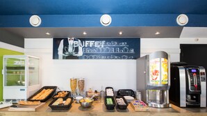 A buffet area with various food items, a coffee machine, and a refrigerator.