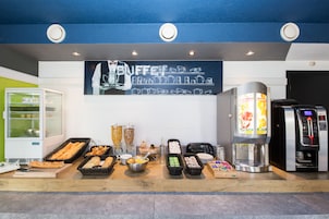 Zona de bufé con diversas opciones de comida, una máquina de café y un refrigerador.