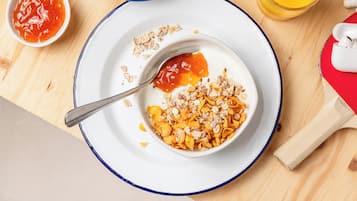Desayuno con un tazón de cereal, una cuchara y un recipiente pequeño de kétchup.