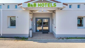 A B&B hotel with a simple facade, a prominent entrance, and a clear sky. - B&B HOTEL Aix-en-Provence Meyreuil Sainte-Victoire (Meyreuil)