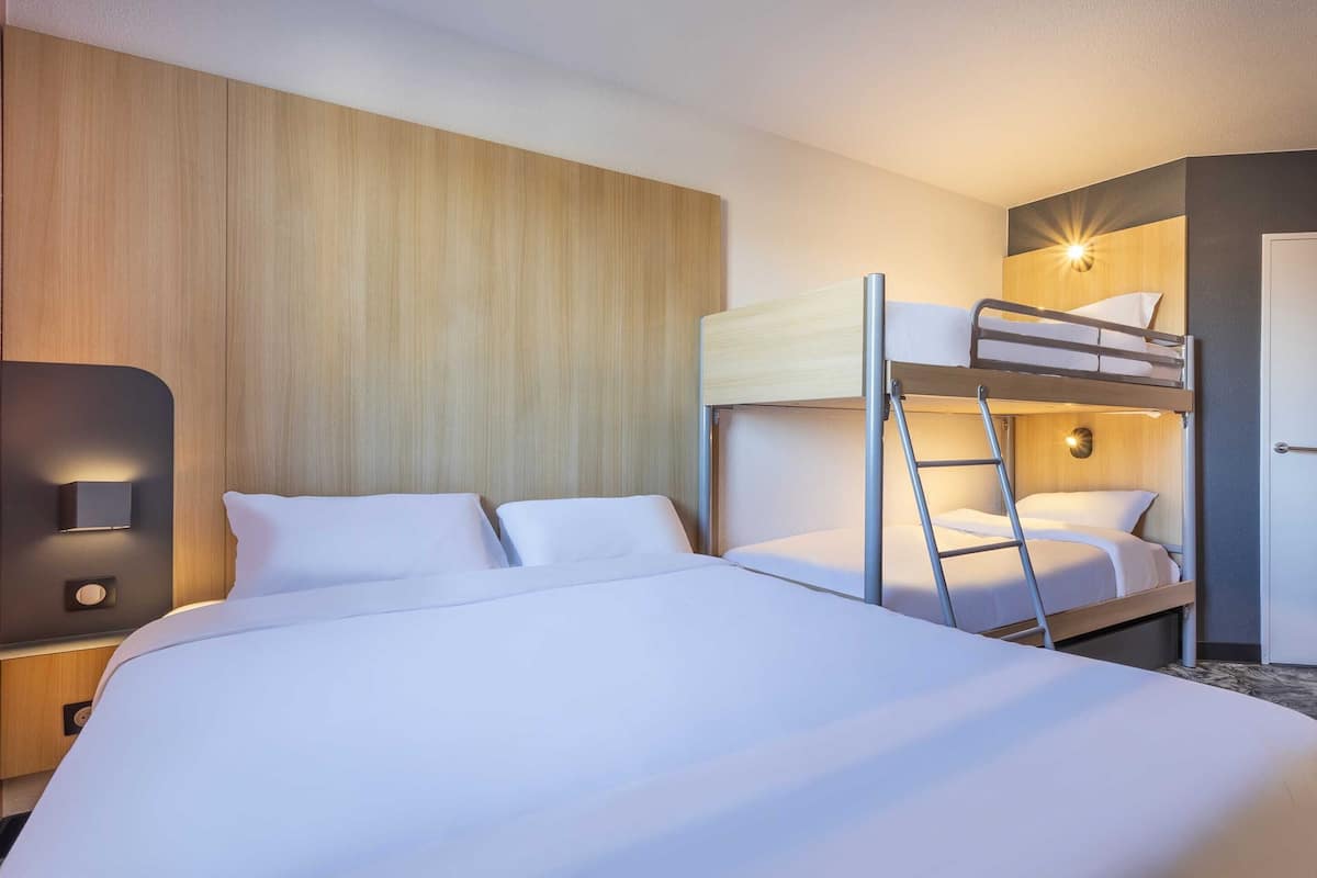 Une chambre d’hôtel avec un lit superposé, un bureau avec une lampe et un mur recouvert de panneaux de bois.