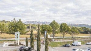 A parking lot with cars, a sign for BAB, and a mountainous background. - B&B HOTEL Aix-en-Provence Meyreuil Sainte-Victoire (Meyreuil)