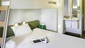 A bunk bed with a bedside table, a green handbag, a white pillow, a magazine, and a mobile phone on the bed. - ibis budget Istres Trigance (Istres)