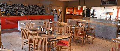 A restaurant with wooden chairs and tables, a counter, and a wall with a black and white mural.