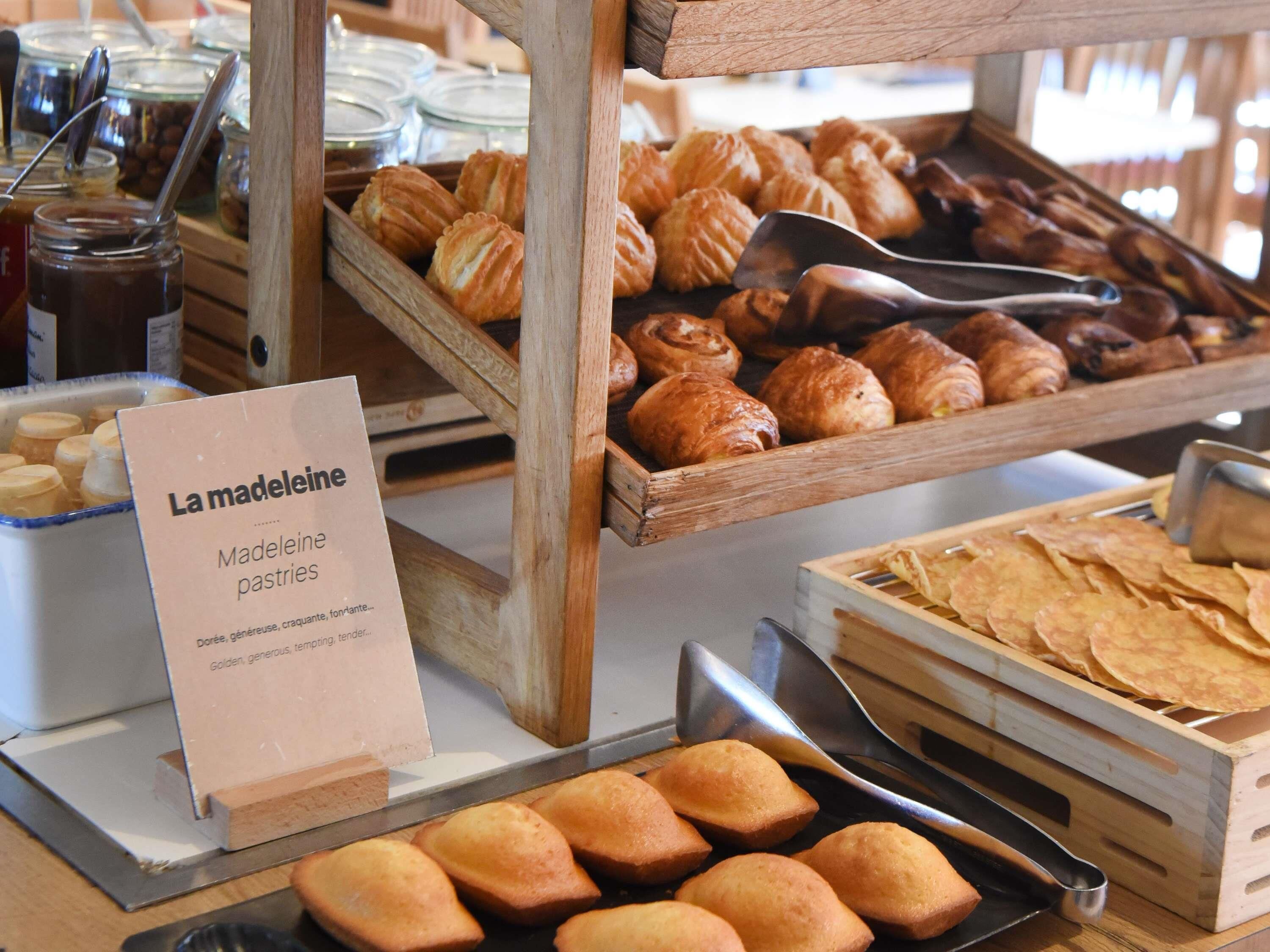 A bakery display with various pastries and a sign indicating 'La Madeleine Madeleine pastries'.