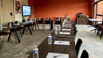 A conference room with multiple tables, chairs, water bottles, and a projector screen.