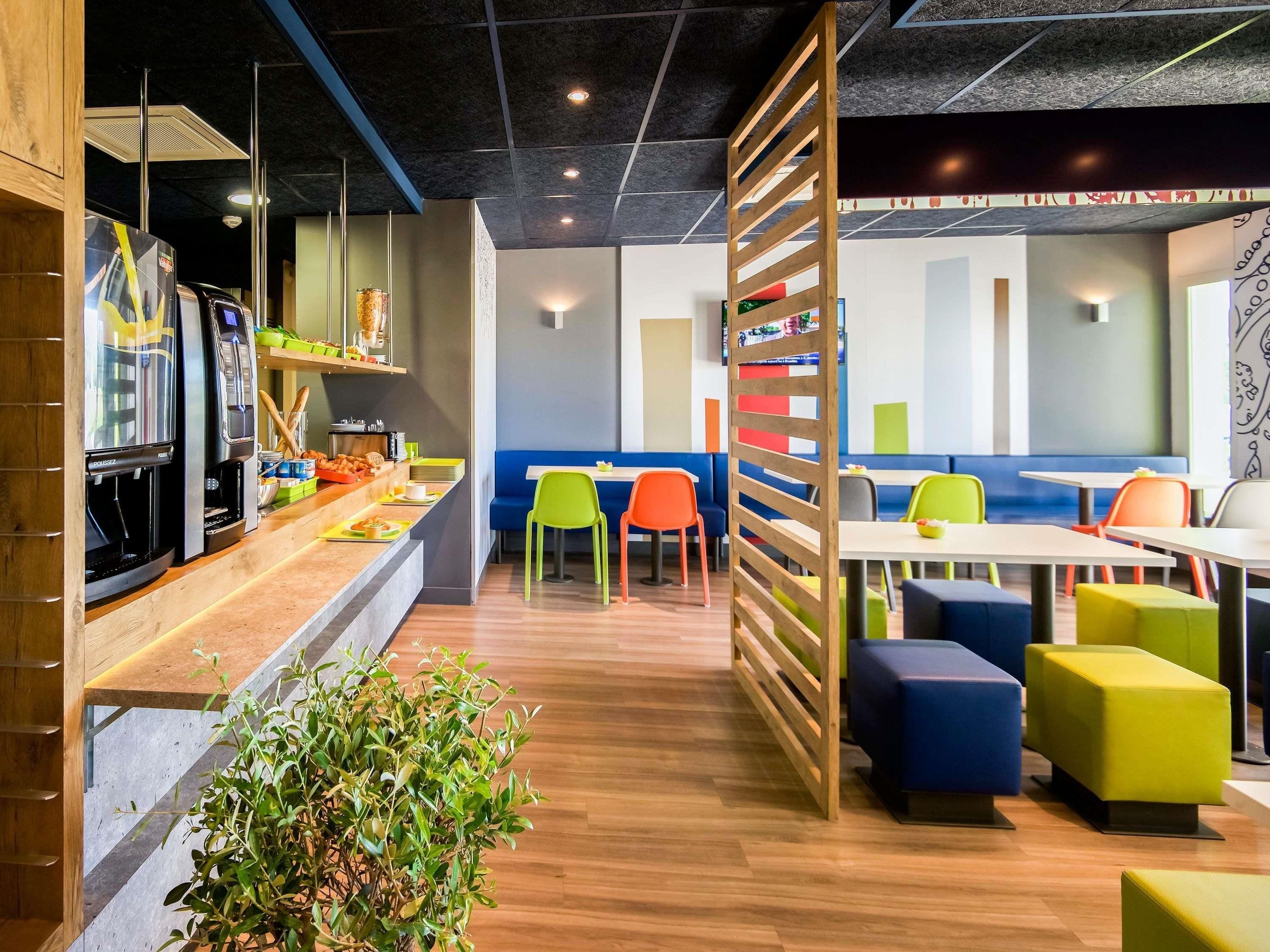 A modern restaurant interior with a counter, seating area, and a decorative plant.