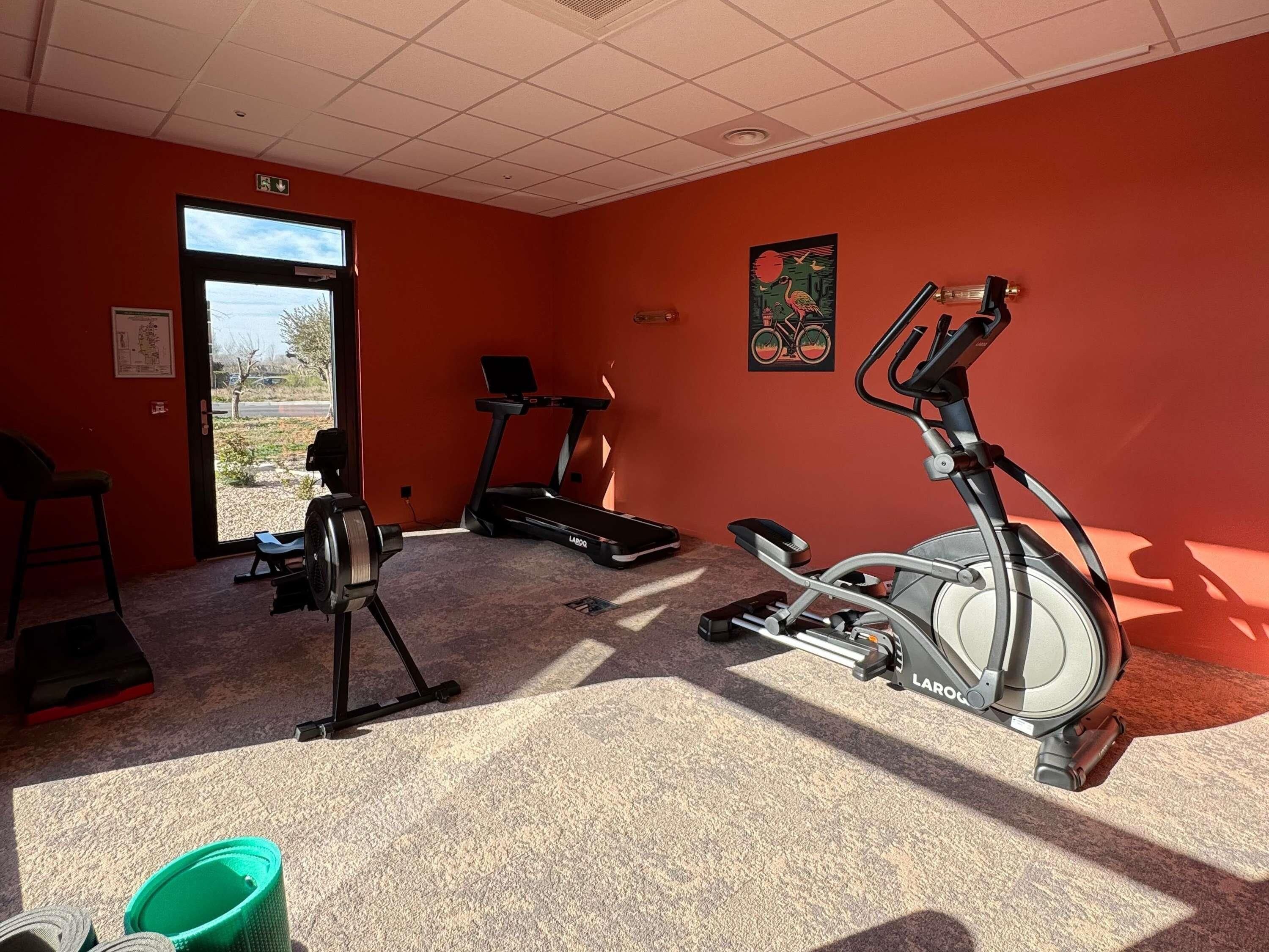 Ett gym med motionscyklar, ett löpband och en dörr som leder ut.