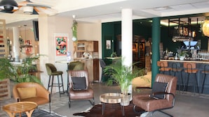 A modern lounge area with leather chairs, a bar, and a variety of plants. - ibis budget Saint Martin de Crau Porte de Camargue (Saint-Martin-de-Crau)
