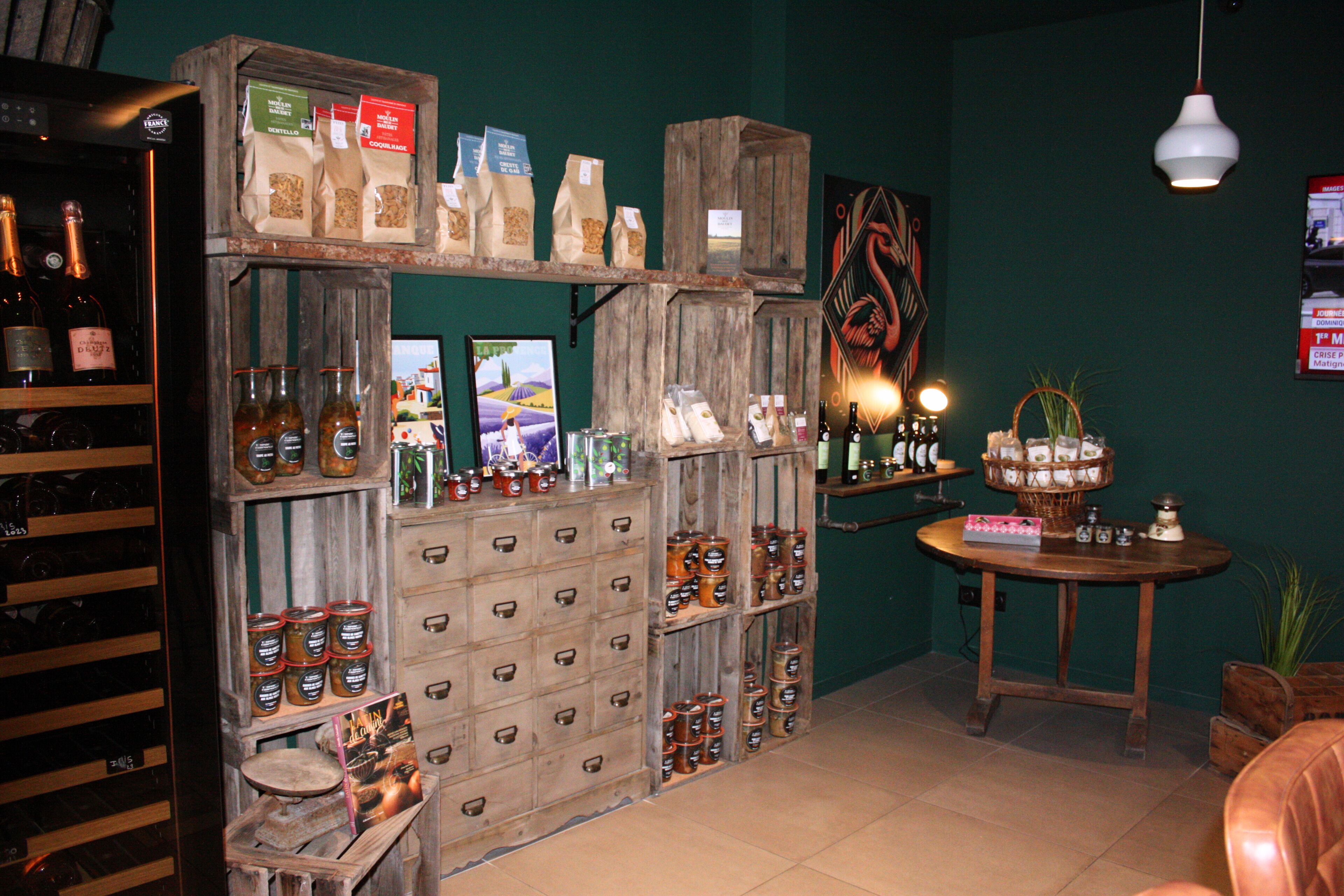 A rustic interior with wooden crates and shelves displaying various bottles and jars, a small table with a basket, and a hanging light fixture.