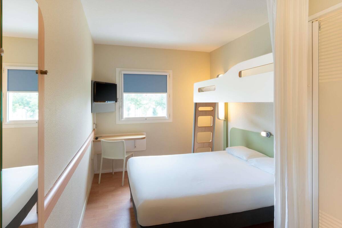 A compact room with bunk beds, a desk, a chair, and a television.