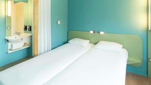 Een hotelkamer met een bed, een badkamer met een wastafel en een spiegel.