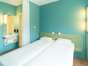 Hotellihuone, jossa on sänky, kylpyhuone, jossa on pesuallas, ja peili.