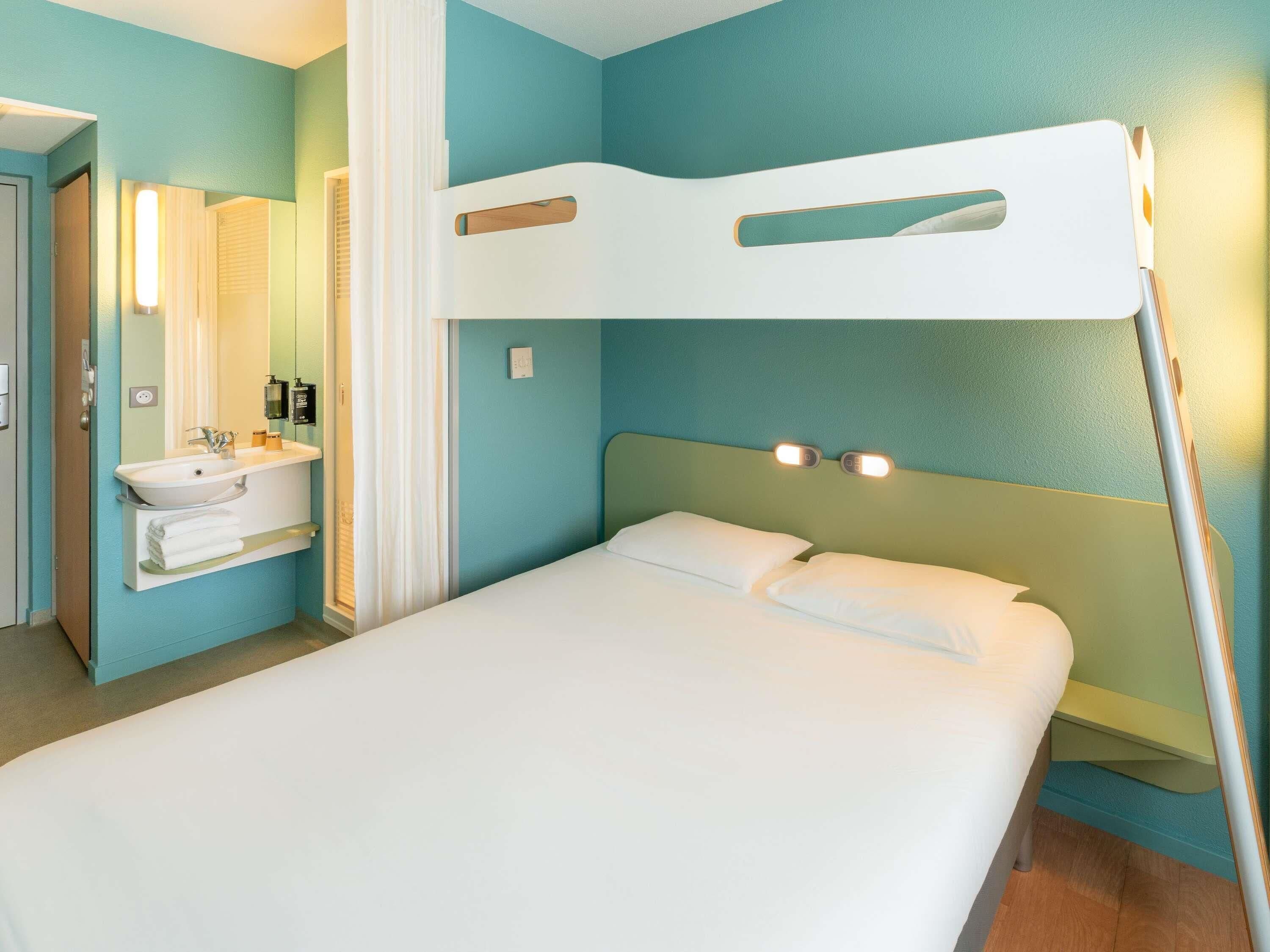 A room with a bunk bed, a sink, and a mirror.