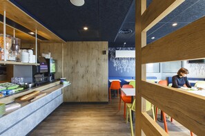 Ein modernes Café mit Holztresen, Sitzbereich und einer blauen Akzentwand.