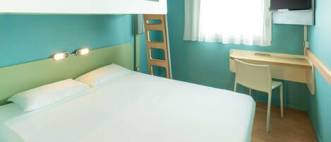 A hotel room with a bed, a desk, a chair, a television, and a window with curtains.