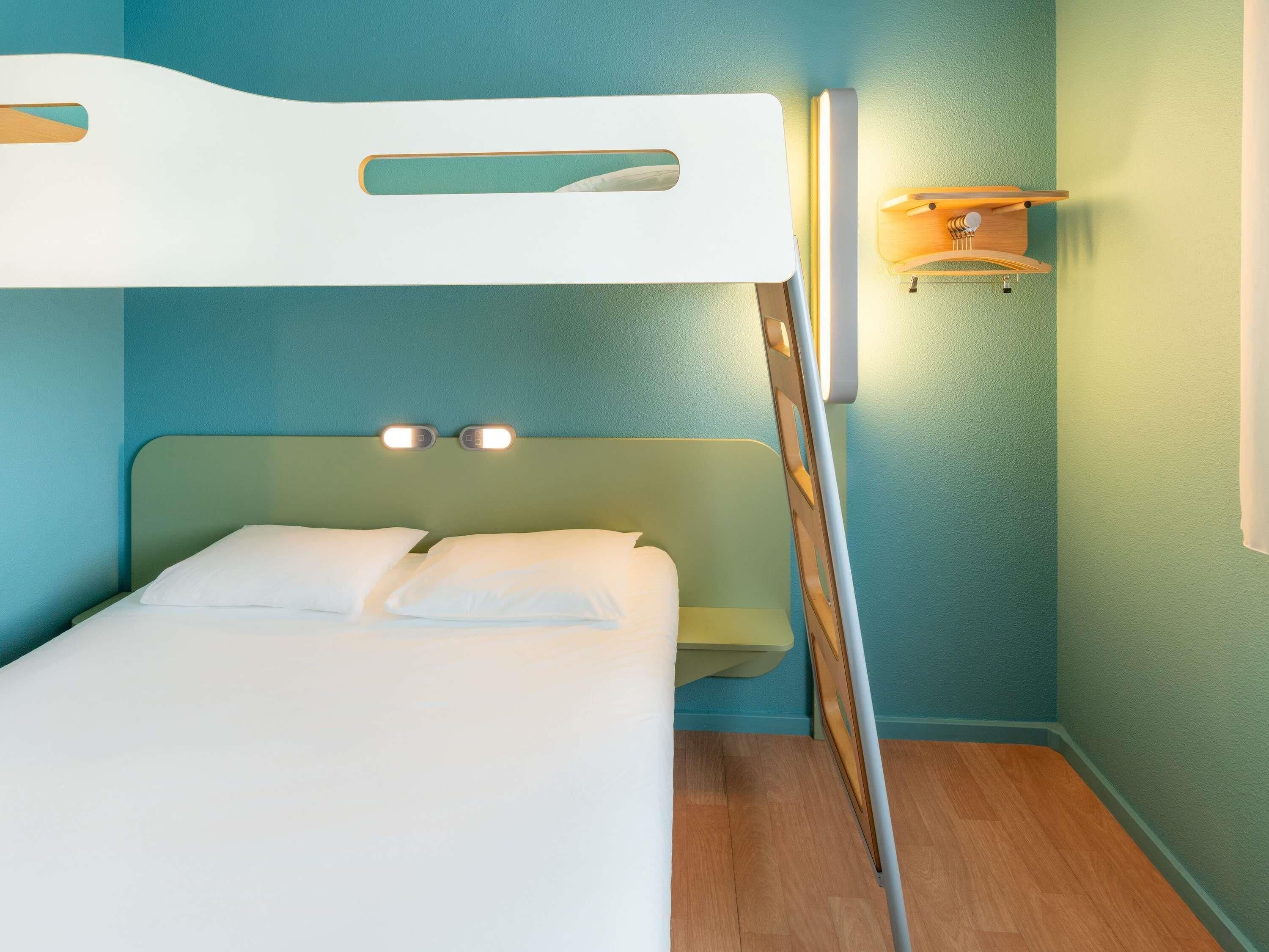 A bunk bed with a headboard, a bedside table, and a wall-mounted light fixture.