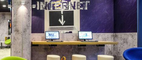 Un espacio de trabajo con dos computadoras, un gran letrero que dice 'INTERNET' y asientos modernos.