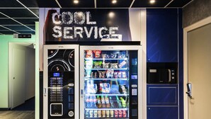 Ein Automatikgerät mit der Aufschrift 'COOL SERVICE' und einer Auswahl an Snacks und Getränken.
