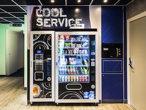 Un distributeur automatique portant l’inscription « SERVICE RAPIDE » et proposant une variété de collations et de boissons.