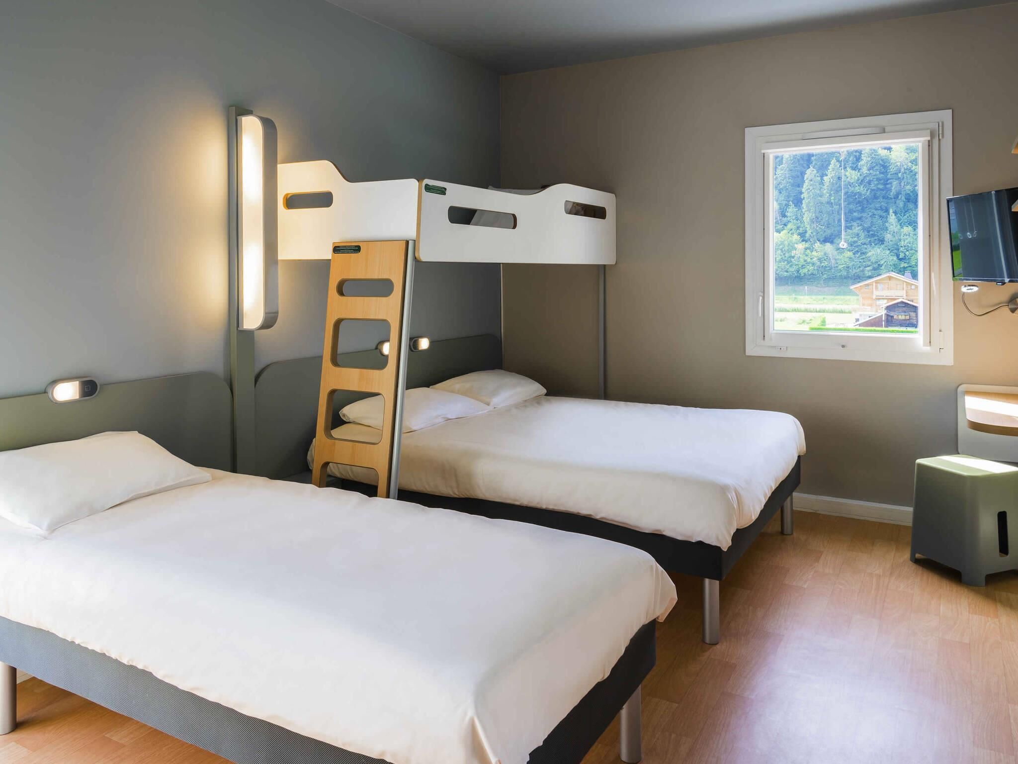 A room with two beds, a ladder, a window with a view, and a TV.