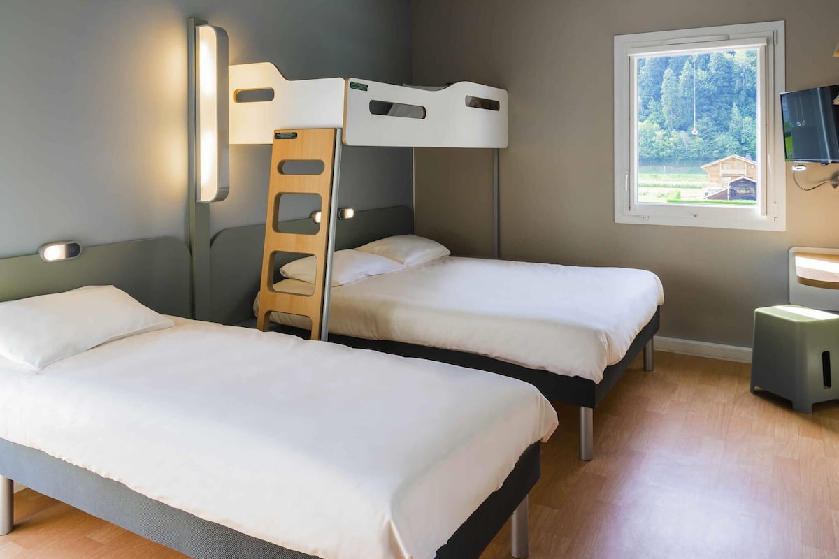 Une chambre avec deux lits, une échelle, une fenêtre donnant sur un beau paysage et un téléviseur.