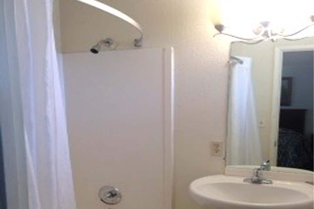 A bathroom with a bathtub, a sink, and a mirror.