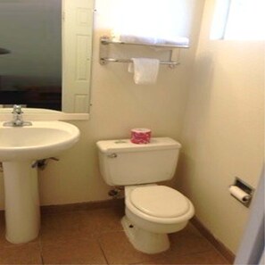 A small bathroom with a sink, toilet, and a window above the toilet. - Cambridge Inn Motor Lodge (Coalinga)