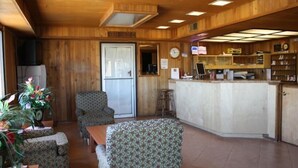 Un intérieur en bois comprenant un espace repas, un bar et un comptoir d’accueil.