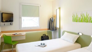 A hotel room with two beds, a desk, a chair, a TV, a window, and a wall art piece. - ibis budget Antibes Sophia Antipolis (Vallauris)