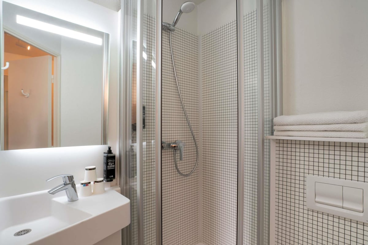 A modern bathroom with a glass-enclosed shower, a white sink, and a mirror.