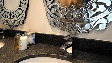 A bathroom with a granite countertop, two sinks, and ornate wall mirrors.