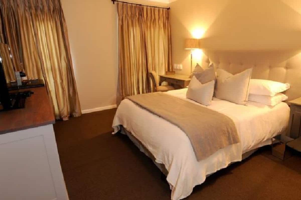 A hotel room with a large bed, two bedside tables, a nightstand, and a desk with a chair.