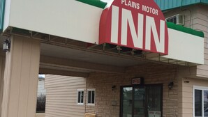 A Plains Motor Inn with a prominent red sign, a brick facade, and a bench outside. - Plains Motor Inn (Stettler)