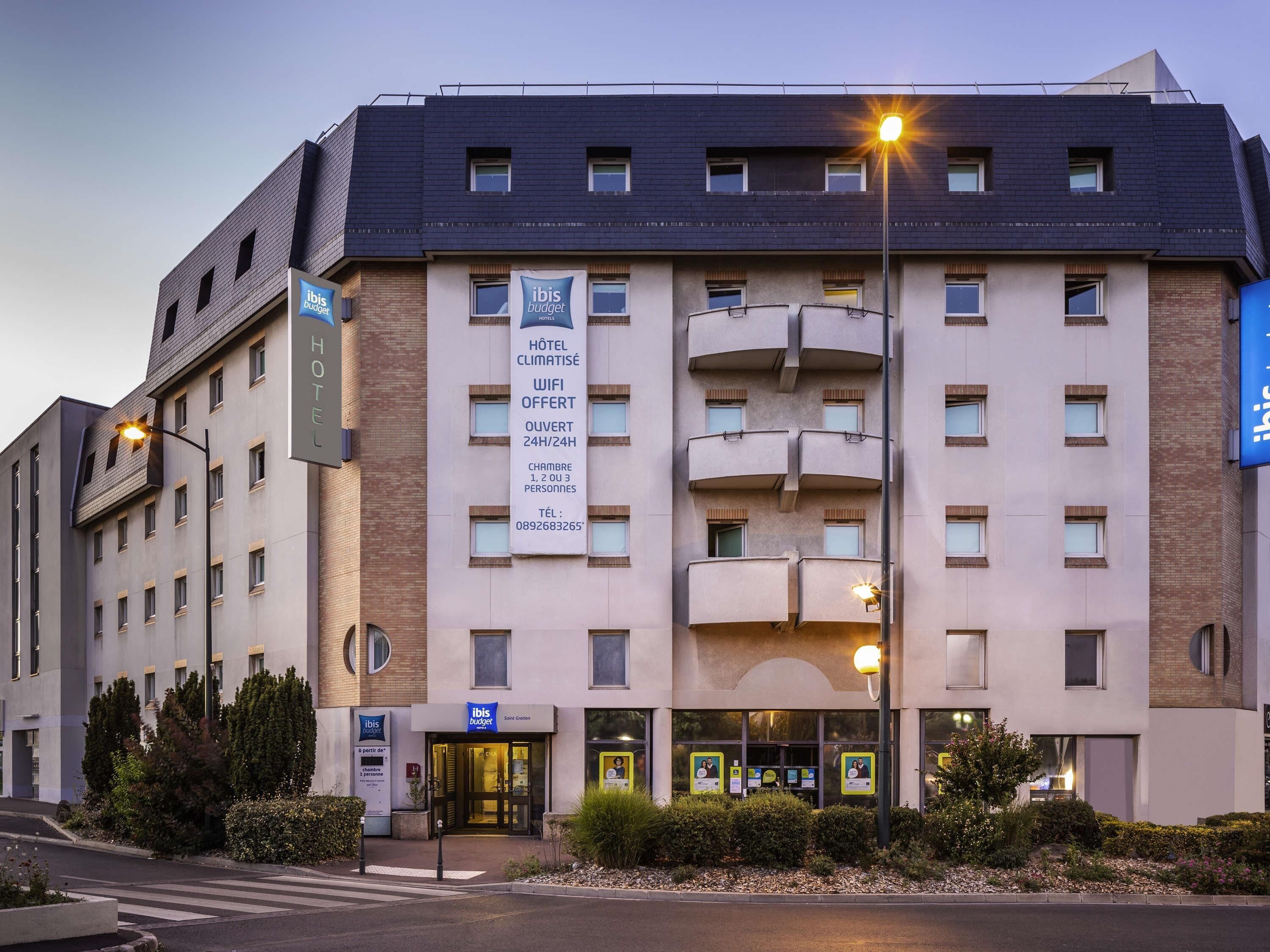 A hotel with a modern design, featuring balconies, a 24/7 WiFi service, and a contact number for inquiries.