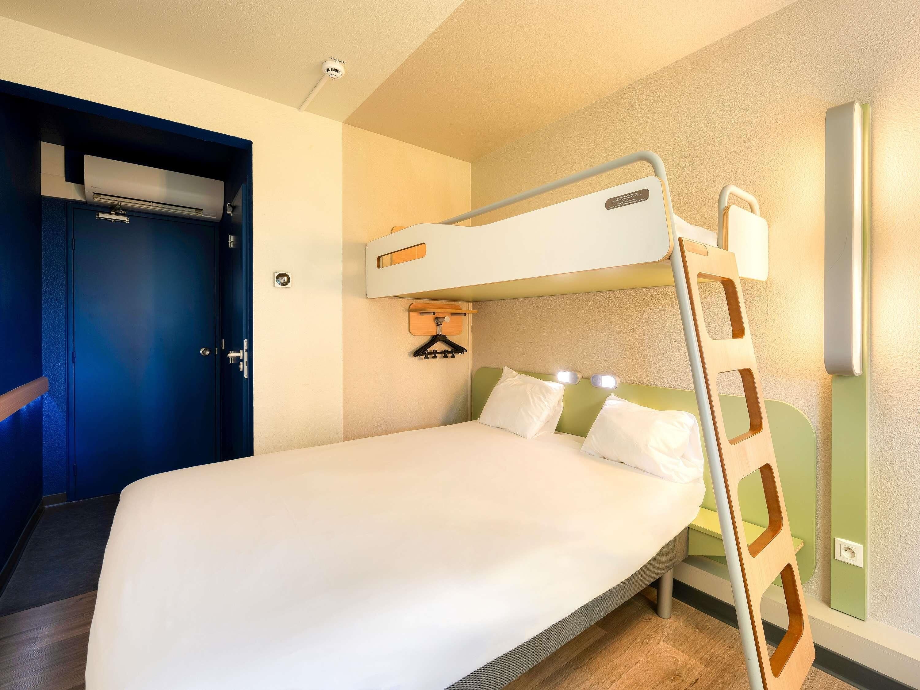 A bunk bed with a ladder, a door, and a wall-mounted air conditioning unit.
