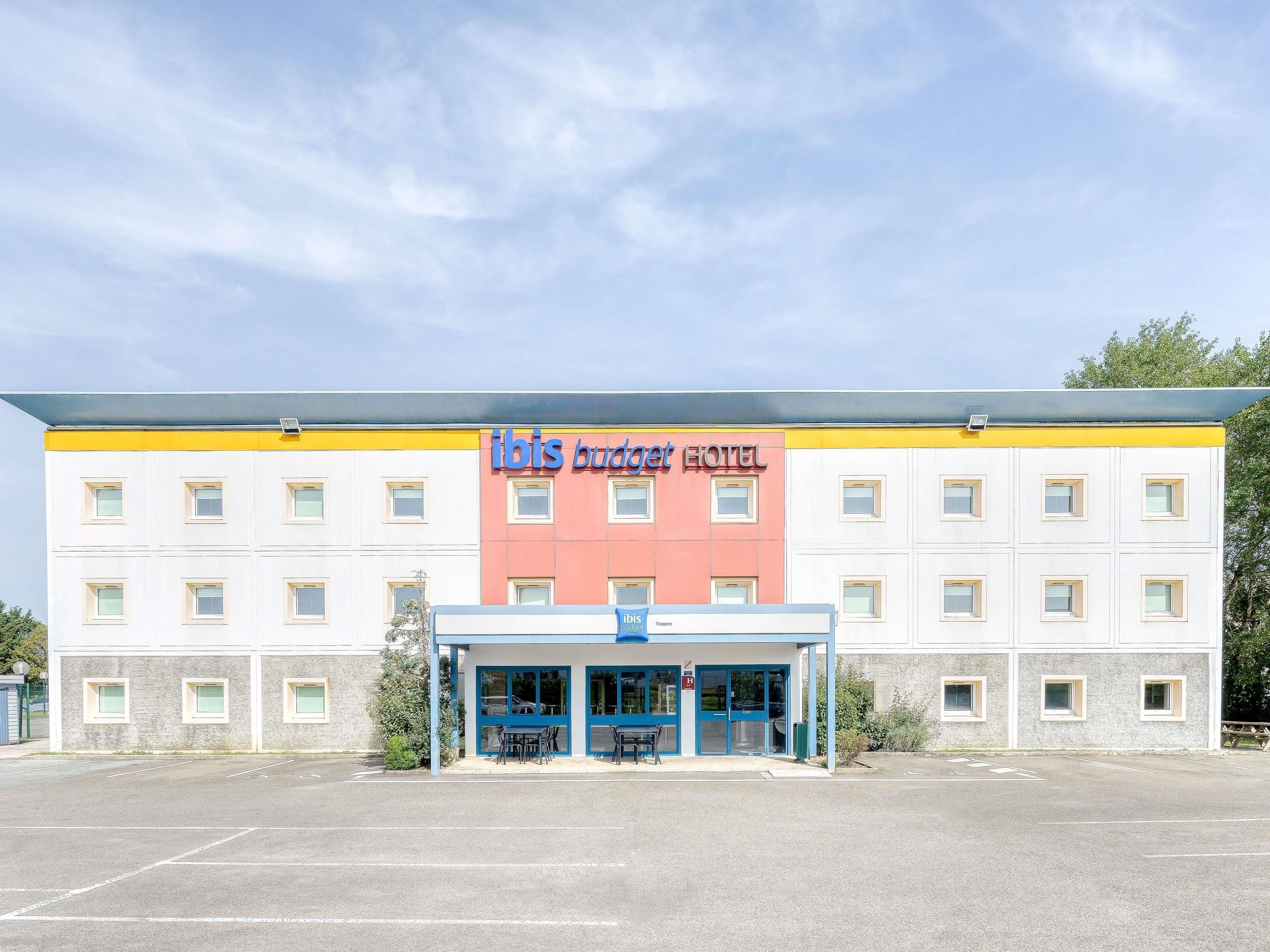 A hotel with a yellow and white facade, a blue entrance, and a sign reading 'ibis budget hotel'.
