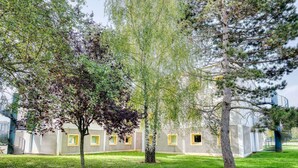 Un bâtiment doté de nombreuses fenêtres et d’un espace verdoyant devant.
