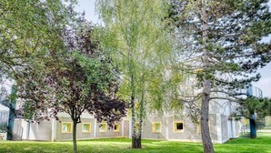 Un bâtiment doté de nombreuses fenêtres et d’un espace verdoyant devant.
