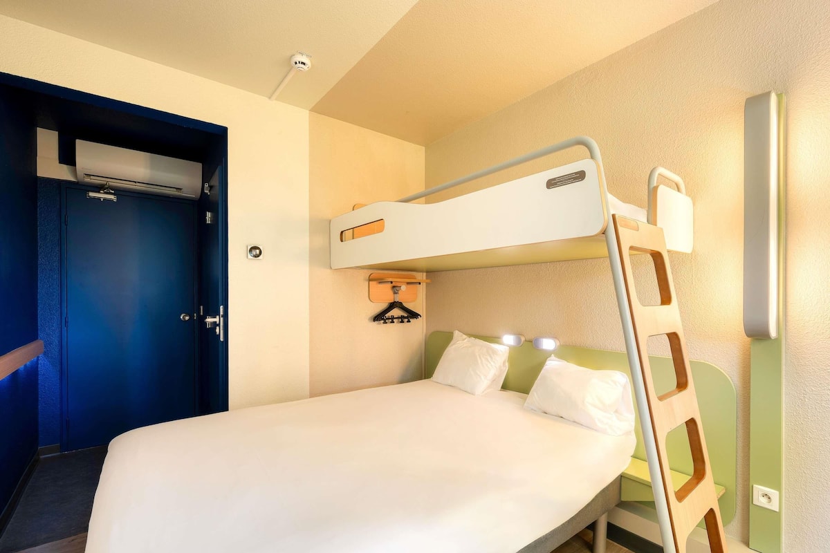 A bunk bed with a ladder, a door, and a wall-mounted air conditioning unit.