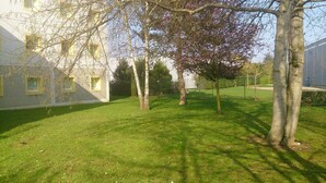 Une cour verdoyante, avec des arbres et un bâtiment doté de nombreuses fenêtres.