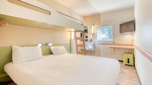 A compact hotel room with a bed, a small bathroom, a TV, and a window. - ibis budget Versailles Trappes (Trappes)