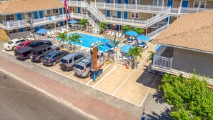 Ein Motel mit Schwimmbad, mehreren Parkplätzen und einem Schild, das Klimaanlage und Zimmerverfügbarkeit anzeigt.